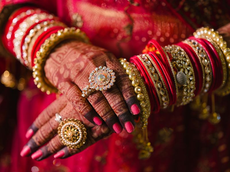 Bridal hands with mehndi wearing gold kundan bangles and rings